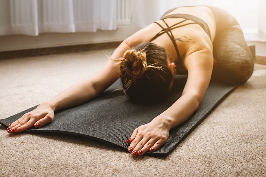 A woman performing child's pose on a black yoga mat