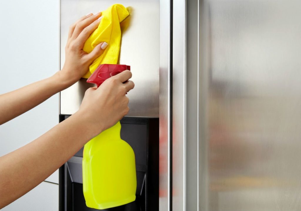 Cleaning a refrigerator's stainless steel door with a yellow cloth