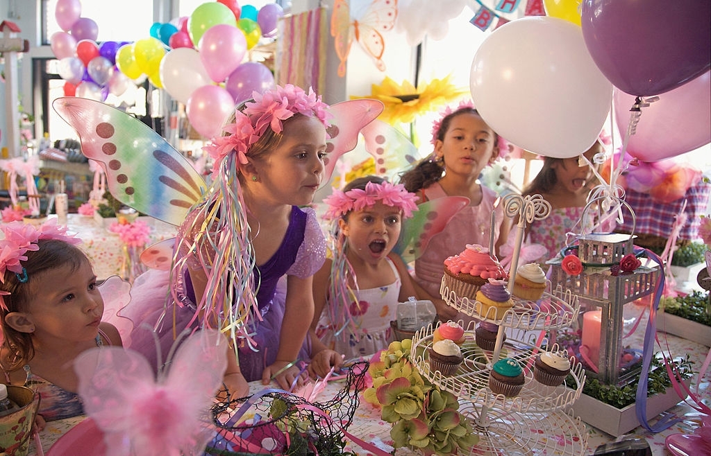 Small children enjoying in a party with multicolored balloons, cupcakes and other party items