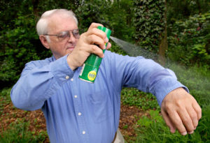 Man spraying a bug spray on his clothes while on a road trip