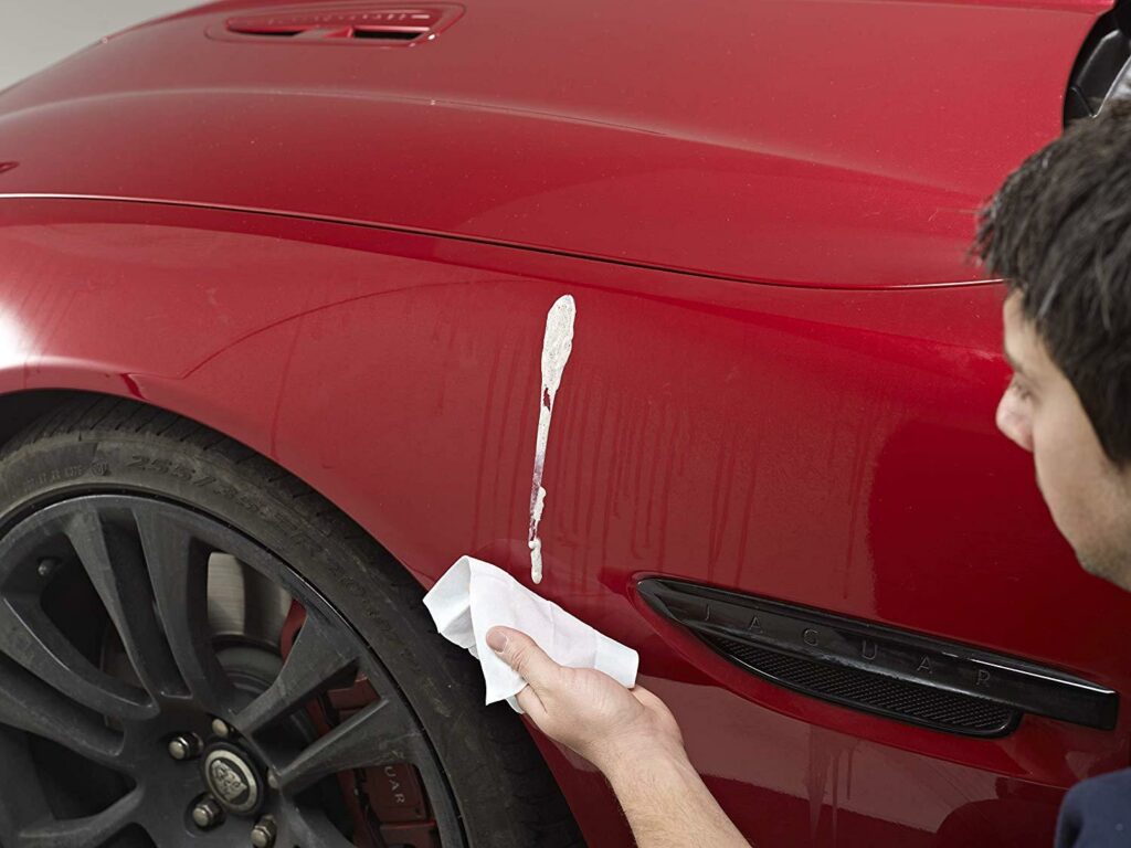 removing bird poop off a red car with wipes