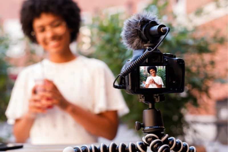 A happy young girl is talking and smiling while making her vlog, expressing her creativity and passion for one of her favorite hobbies for women in 20s