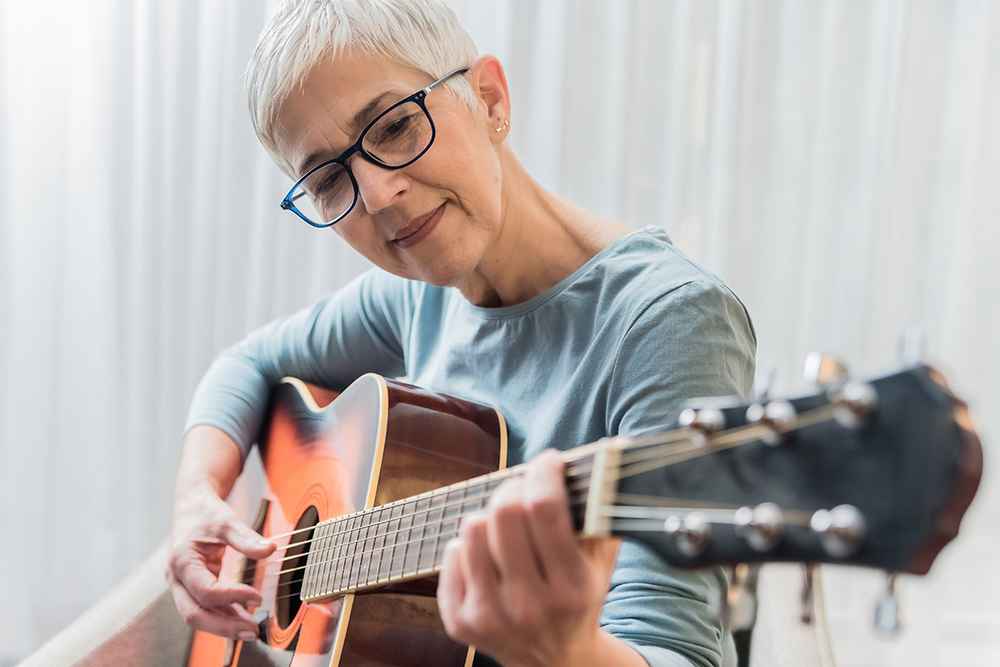 Women in their 50s playing the guitar, enjoying one of the timeless hobbies for women in 50s