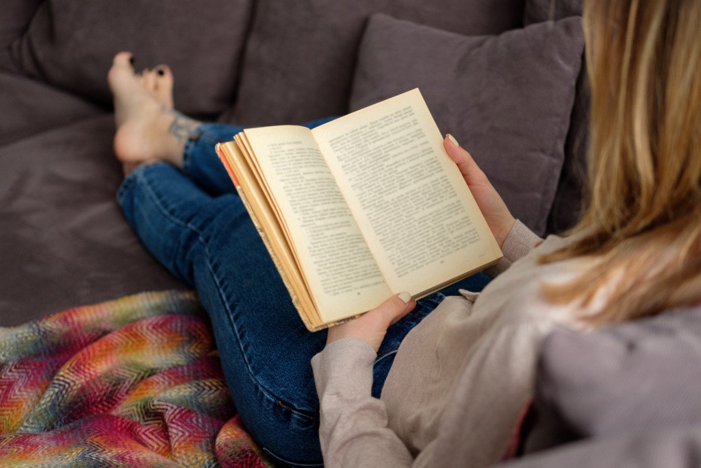 Women reading a book on sofa indulging in one of the favorite hobbies for women