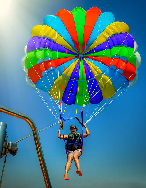 A young women having a fantastic time pursuing one of her favorite hobbbies for women parasailing and embracing the thrill of flying high above the water