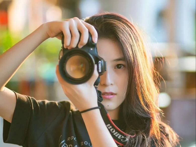 A young girl taking pictures with a camera, exploring photography, and trying out different hobbies for women.
