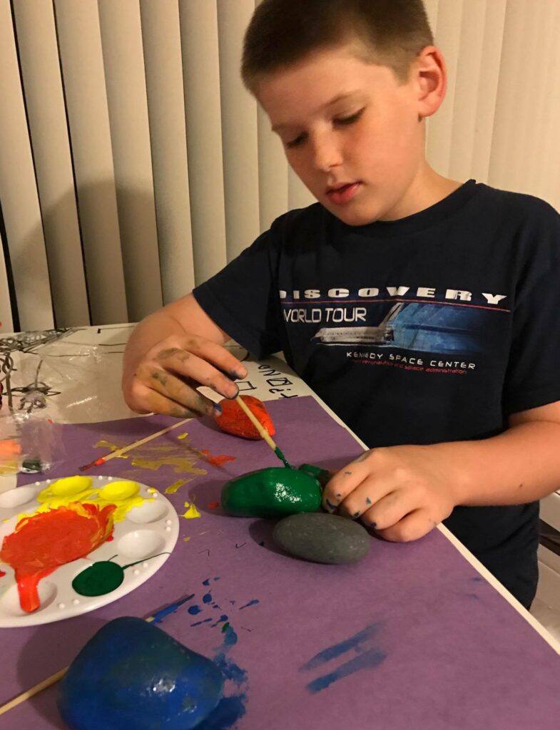 Photo of a boy painting rocks - a fun job for 8 year olds